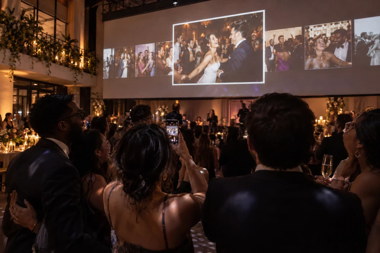 Wedding guests enjoying a live photo slideshow projected at their venue